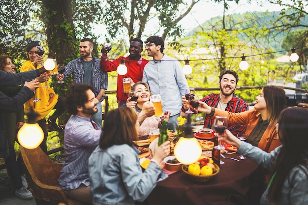 Una giornata tranquilla con gli amici che brindano insieme a vino e birra al tramonto concetto di stile di vita di persone che si divertono a mangiare nel fine settimana nel cortile dell'agriturismo in campagna