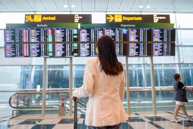 Una giovane bella donna che cammina con la valigia fa il check-in all'aeroporto internazionale