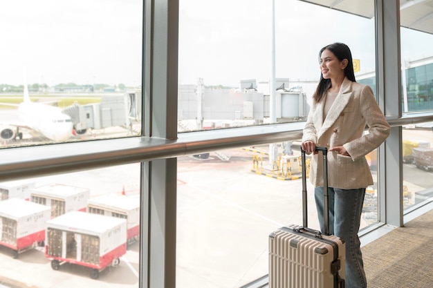 Una giovane bella donna che cammina con la valigia fa il check-in all'aeroporto internazionale