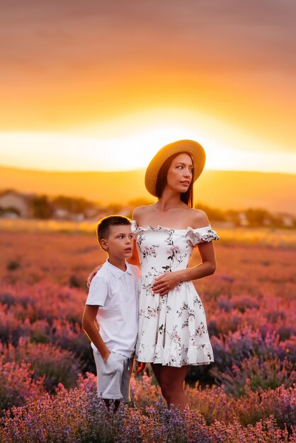 Una giovane bella donna con il suo giovane figlio sta camminando attraverso un bellissimo campo di lavanda e si gode il profumo dei fiori. Riposo e bella natura. Unità con la natura e armonia.