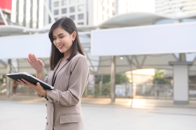 Una giovane bella donna d'affari sta usando il tablet nella città moderna