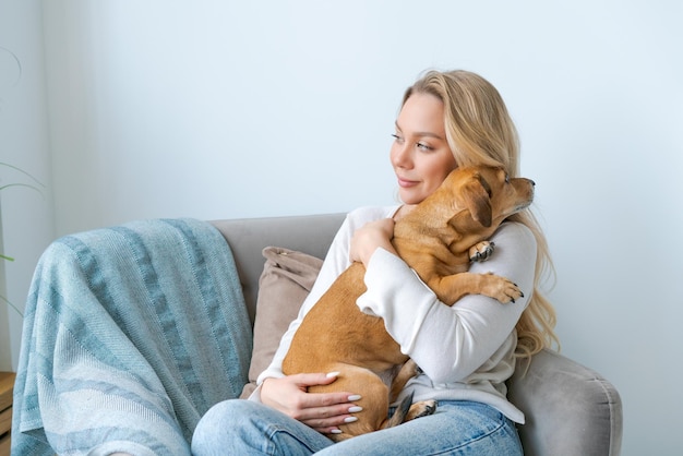 Una giovane bella donna in abiti casual abbraccia e accarezza il suo amato cane seduto