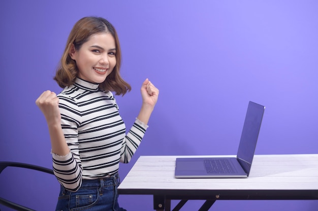 Una giovane bella donna sta lavorando con il suo computer su sfondo blu.