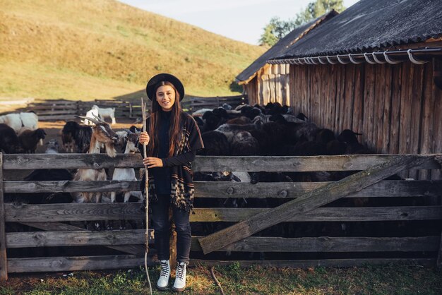 Una giovane bella donna vicino a un recinto con le capre