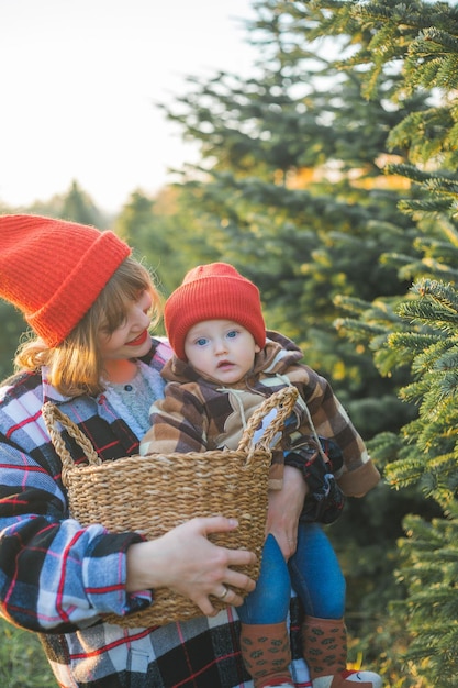 Una giovane bella famiglia sceglie un albero di Natale nel mercatino Vacanze invernali festive per genitori e bambini piccoli eco friendly