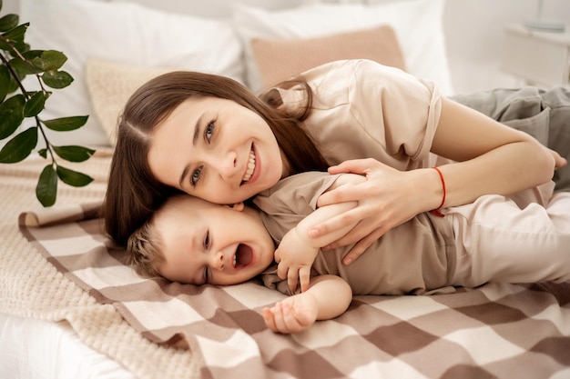 Una giovane bella madre con un bambino abbracciato sul letto a casa in camera da letto la cura e l'amore della madre ritratto di una madre felice con una maternità sana bambino