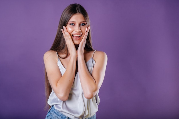 Una giovane bella ragazza mostra emozioni e sorrisi in studio su uno sfondo viola