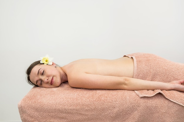 Una giovane bella ragazza si trova su un lettino da massaggio in un salone termale prima di una procedura La ragazza sta aspettando un massaggio