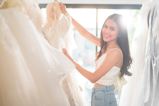 Una giovane bella sposa che sceglie un abito da sposa in studio di nozze, concetto di matrimonio