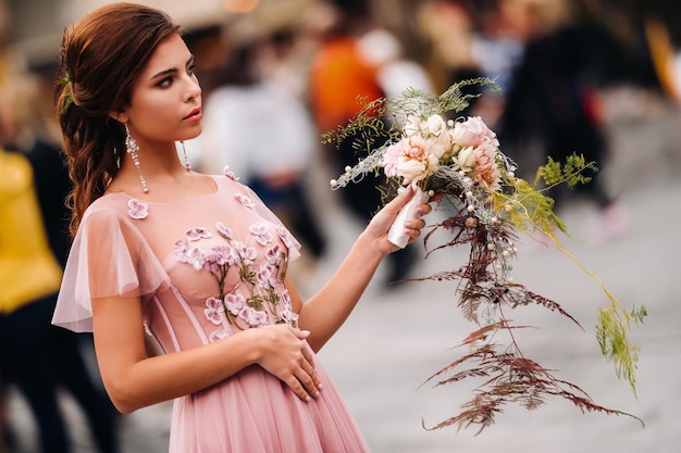 Una giovane bella sposa si trova al centro della città vecchia di Firenze in Italia. Sposa in un bellissimo vestito rosa con un bouquet in Tuscany.Italy.