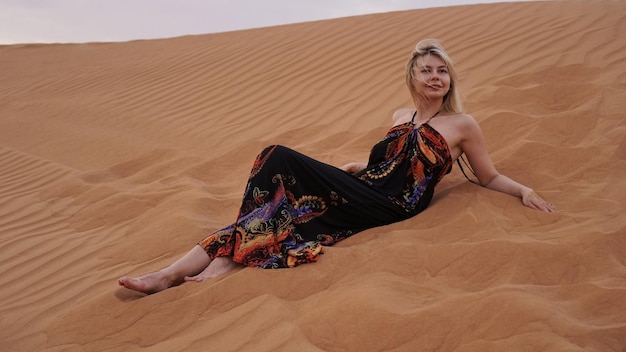 Una giovane bionda giace su un pesce nel deserto Donna tra le dune