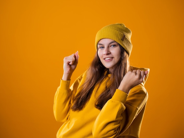 Una giovane bruna allegra in abiti luminosi balla e si diverte con una giovane donna con un cappuccio giallo...