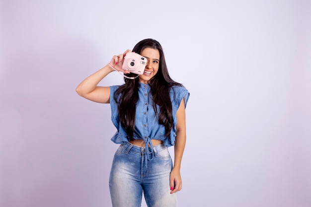 Una giovane bruna posa con una foto di alta qualità della fotocamera polaroid