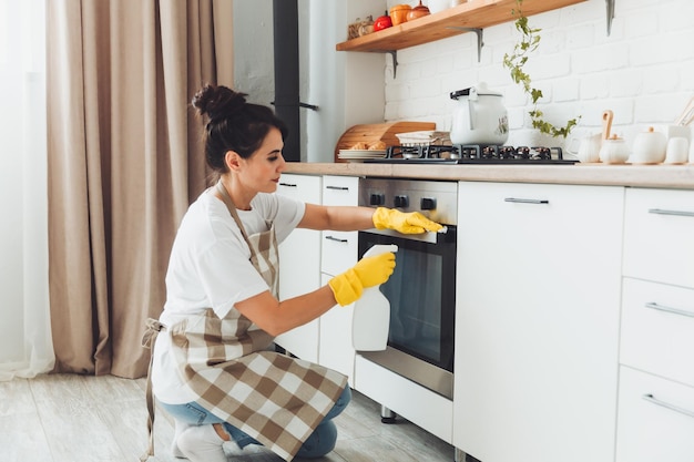 Una giovane bruna pulisce la cucina una donna in guanti lava la stufa la ragazza pulisce la casa