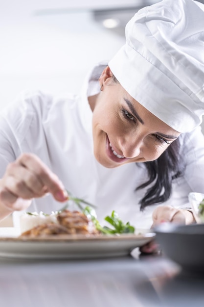 Una giovane chef femminile finisce il pasto con le erbe nella cucina del ristorante Primo piano