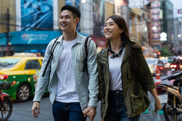 Una giovane coppia asiatica attiva viaggia in città per un viaggio di luna di miele di notte Attraente nuovo matrimonio uomo e donna backpacker turisti che camminano per strada si divertono a passare il tempo insieme in vacanza di San Valentino