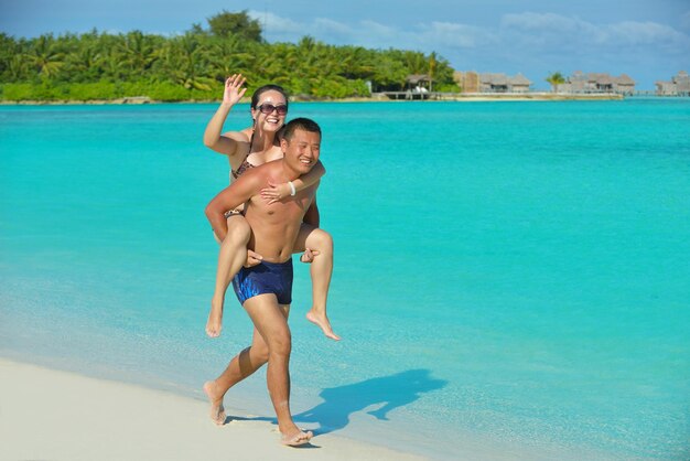 Una giovane coppia asiatica felice si diverte e trascorre un periodo romantico in estate su una bellissima spiaggia di sabbia bianca.