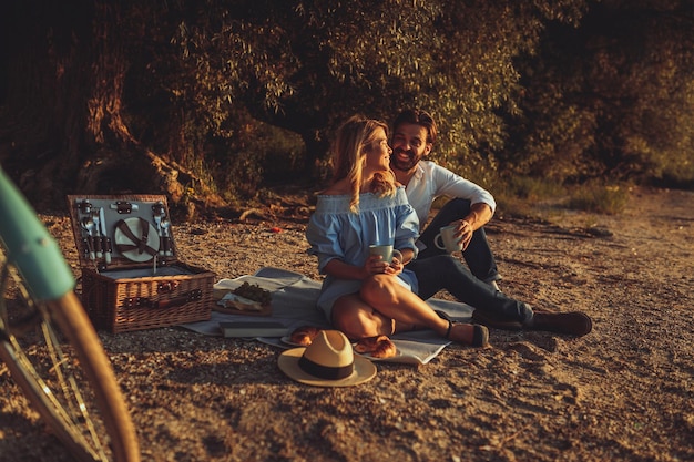 Una giovane coppia che fa un picnic in spiaggia