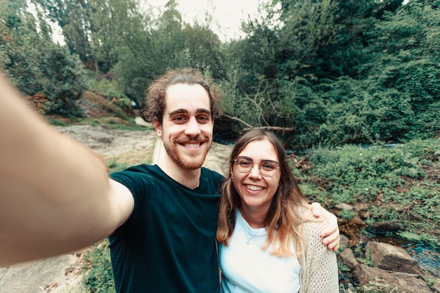 Una giovane coppia che prende un selfie nella foresta mentre sorride