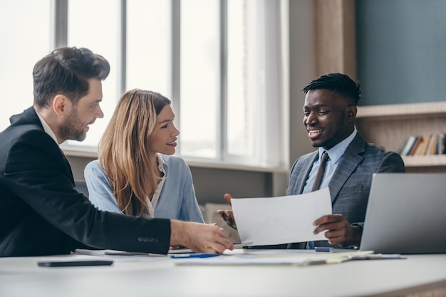 Una giovane coppia concentrata ascolta un consulente finanziario mentre sono seduti insieme alla scrivania dell'ufficio