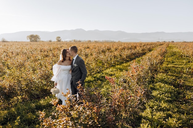 Una giovane coppia di sposi appena sposati, sposo e sposa, posano all'aperto il giorno del loro matrimonio.