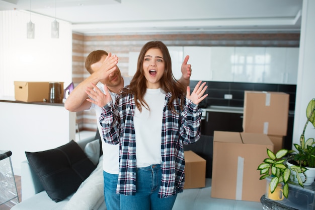 Una giovane coppia di sposi nel salotto di casa si trova vicino a scatole non imballate. hey sono contenti della nuova casa. Traslocare, acquistare una casa, concetto di appartamento.