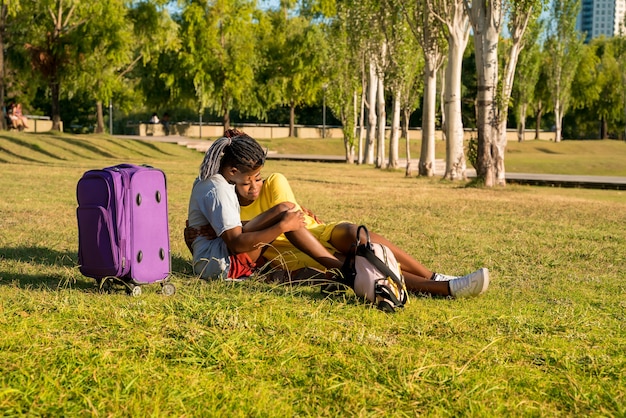 Una giovane coppia felice con i bagagli che si rilassano in un parco