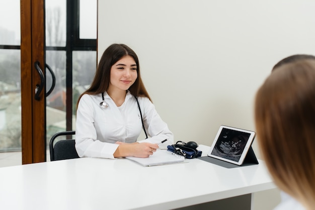 Una giovane coppia in attesa di un bambino di consultare un ginecologo dopo un'ecografia. Gravidanza e assistenza sanitaria