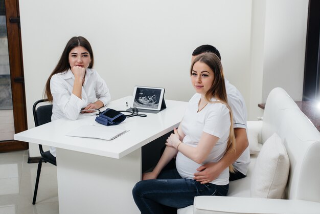 Una giovane coppia in attesa di un bambino di consultare un ginecologo dopo un'ecografia. Gravidanza e assistenza sanitaria