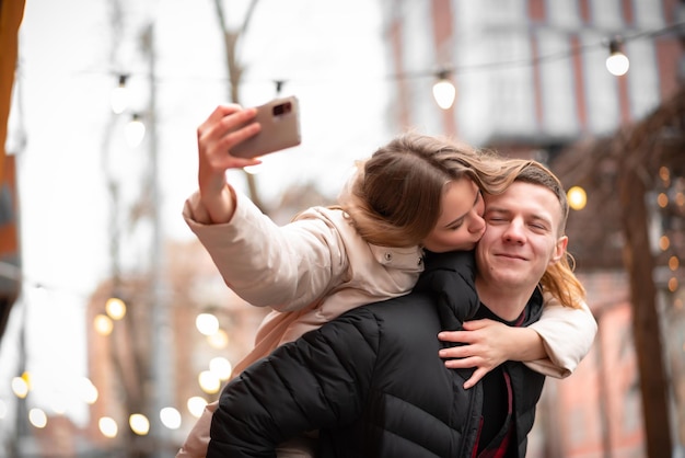 Una giovane coppia si diverte in vacanza in inverno. Le persone amano viaggiare e vivere insieme. Stile di vita felice per un uomo che porta una donna sulla schiena