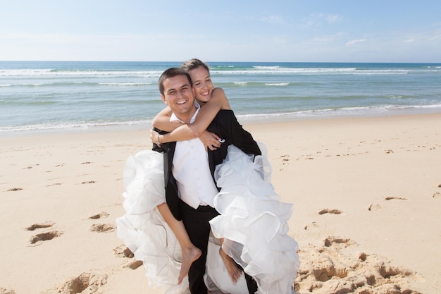 Una giovane coppia si è appena sposata su una spiaggia sulle spalle