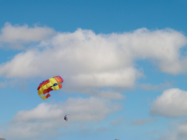 Una giovane coppia sta volando nel cielo blu usando un paracadute colorato