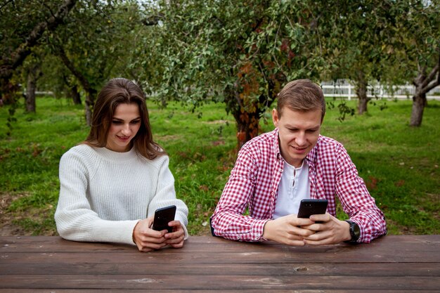 Una giovane coppia trascorre del tempo insieme nel parco seduta a un tavolo di legno e guardandomi