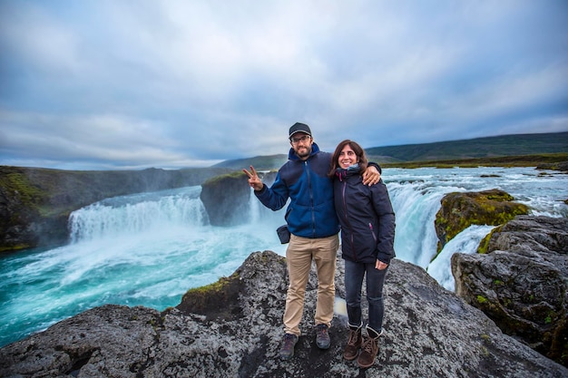 Una giovane coppia turistica guardando la cascata Godafoss dall'alto dell'Islanda