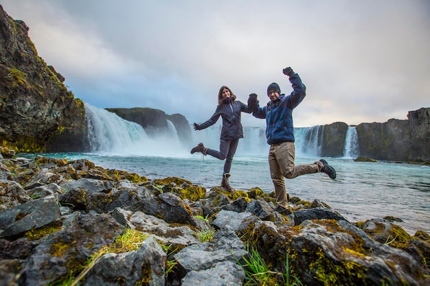 Una giovane coppia turistica guardando la cascata Godafoss dall'alto dell'Islanda