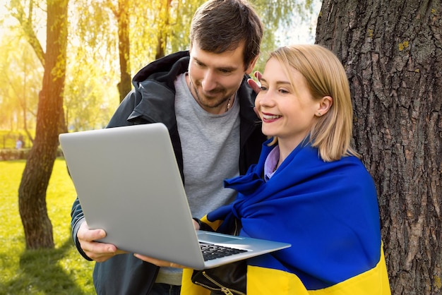 Una giovane coppia ucraina felice sta effettuando una videochiamata su un laptop nel parco in una giornata di sole