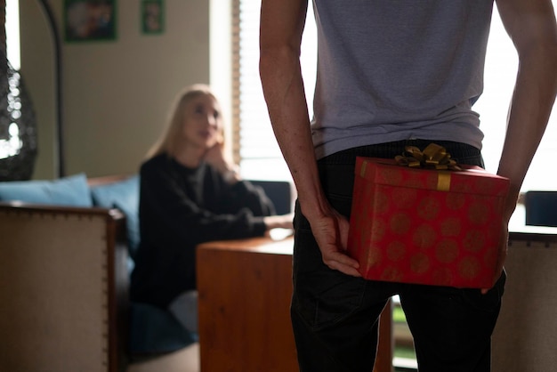 Una giovane coppia, un uomo che tiene una confezione regalo dietro la schiena, facendo una sorpresa alla fidanzata