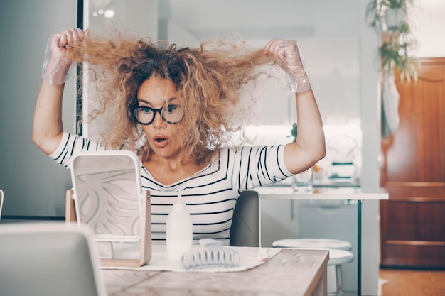 Una giovane donna a casa che sembra in cattive condizioni dei suoi capelli pronta per l'uso e applica il trattamento di bellezza da sola seduta al tavolo Acconciatura per la cura di sé al coperto nello stile di vita dell'appartamento Persone indipendenti