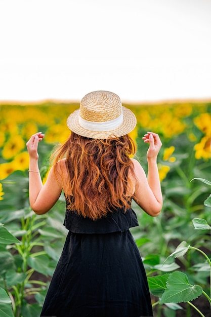 Una giovane donna affascinante in un vestito in un campo di girasoli