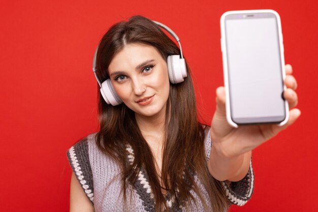 Una giovane donna ascolta la musica con le cuffie sul suo cellulare