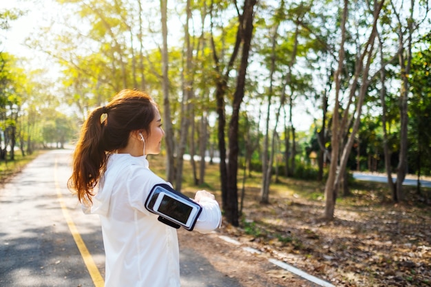 Una giovane donna asiatica allunga le braccia prima di correre nel parco cittadino