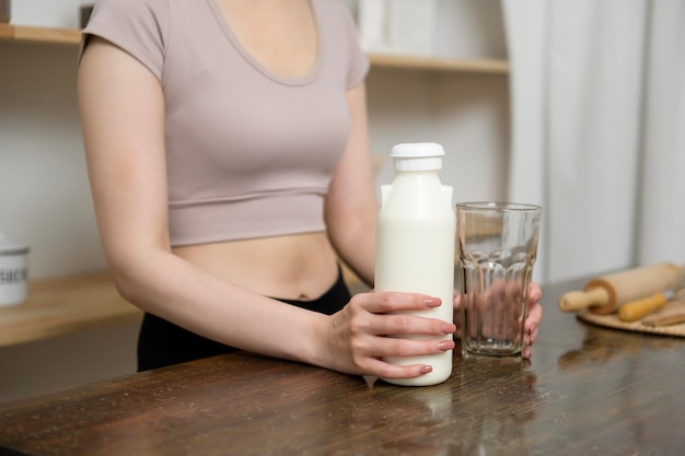 Una giovane donna asiatica in abbigliamento sportivo che beve latte in cucina a casa concetto di stile di vita sano