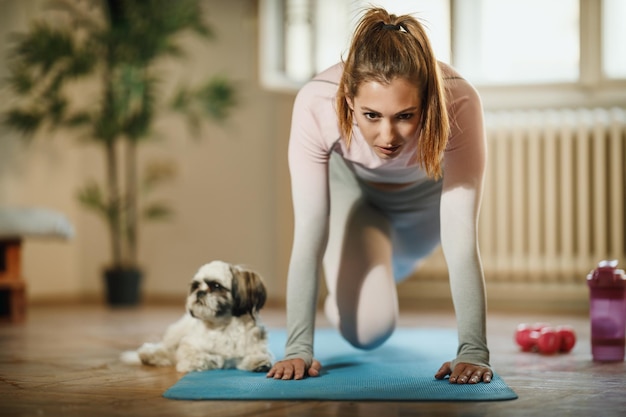 Una giovane donna attraente che fa allenamento fitness a casa durante il giorno.