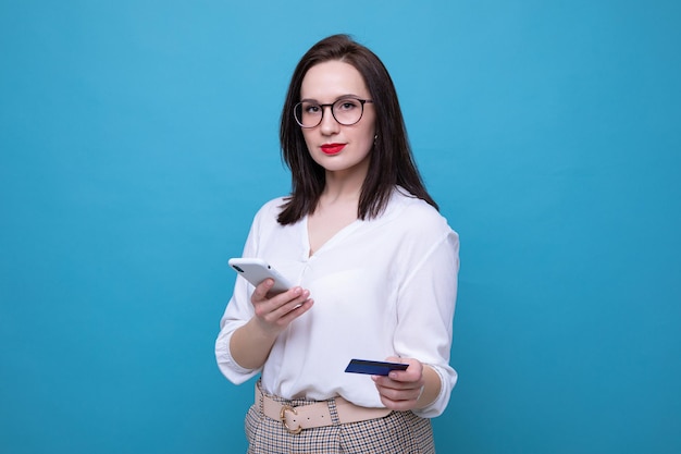 Una giovane donna bruna effettua un ordine online utilizzando il telefono e la carta di credito