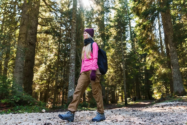 Una giovane donna cammina attraverso la foresta con uno zaino Stile di vita attivo