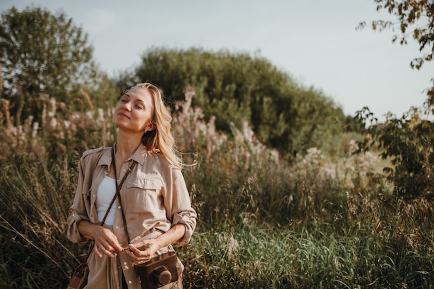 Una giovane donna cammina con una macchina fotografica retrò e scatta foto della natura