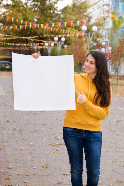 Una giovane donna caucasica punta il dito su un foglio di carta bianco e sorride