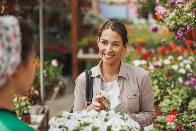 Una giovane donna che acquista in vaso da una giovane imprenditrice in un garden center.