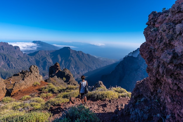 Una giovane donna che cammina in un punto di vista naturale della Caldera de Taburiente durante il trekking vicino a Roque de los Muchachos un pomeriggio d'estate, La Palma, Isole Canarie. Spagna