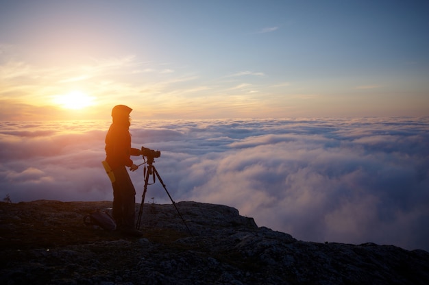 Una giovane donna che fa un film tra le montagne nebbiose al tramonto